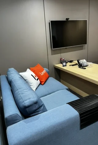 Sala de descanso com sofá azul, almofada da Leven e televisão