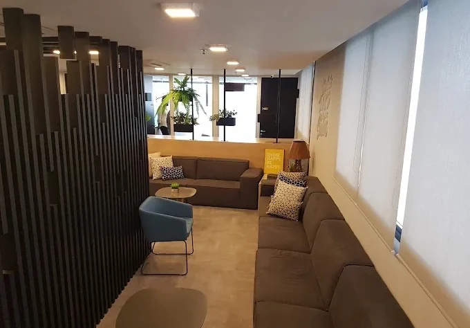 Sala de estar do escritório da Leven com sofás e divisória de ripas de madeira