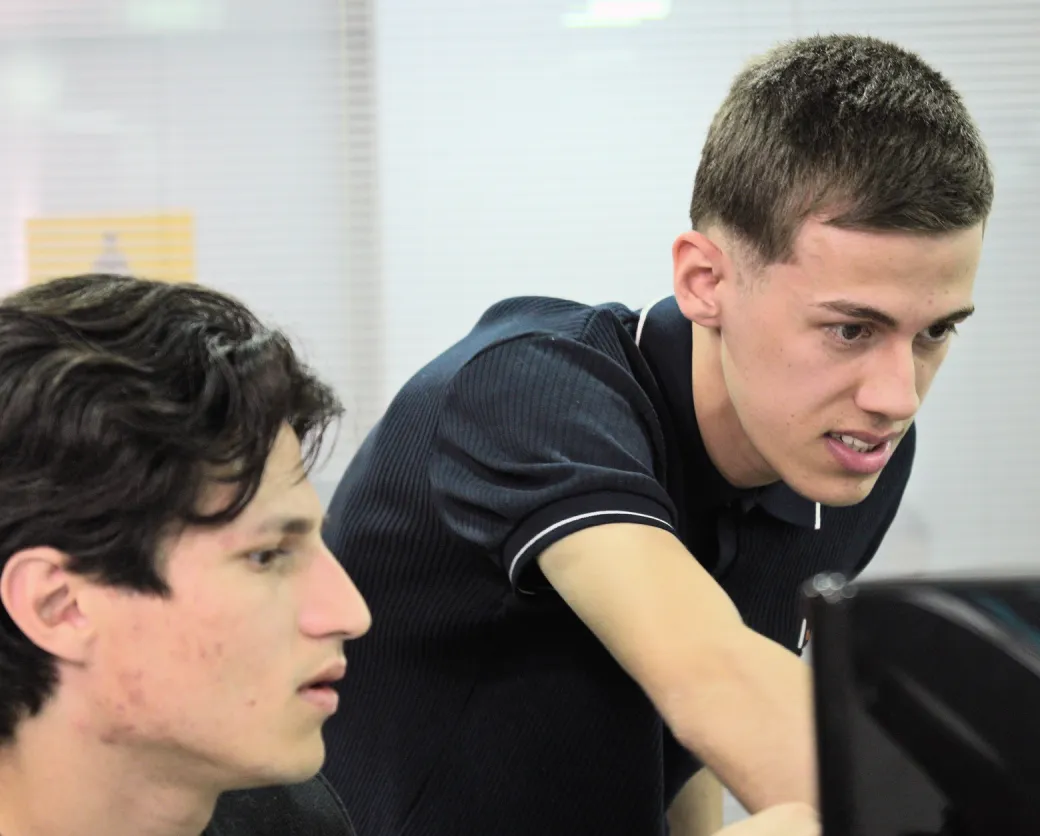 Duas pessoas do time de desenvolvimento diante de um monitor