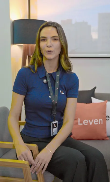 Colaboradora da Leven sentada numa poltrona, com uma almofada da Leven ao fundo