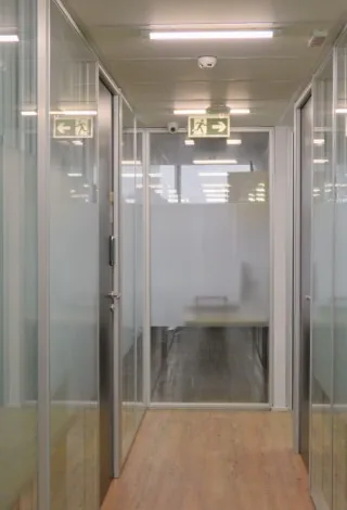 Corredor do escritório da Leven com salas de vidro dos dois lados